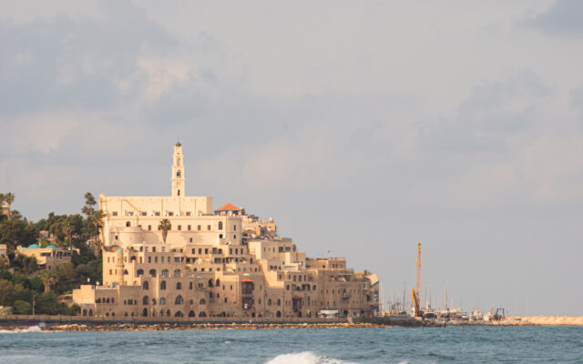 Ancient Jaffa Old City rising from Mediterranean Sea waves at golden hour morning light Tel Aviv Israel