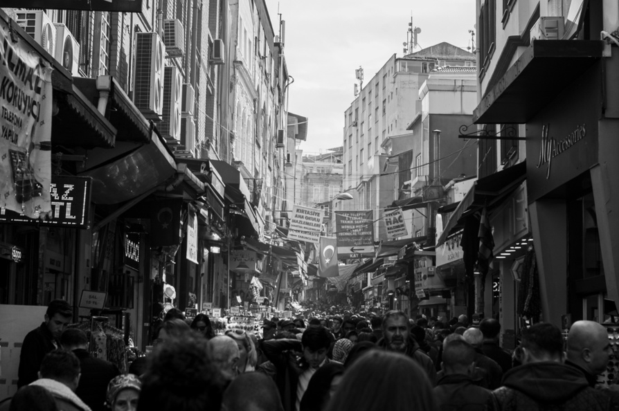 Crowded Istanbul bazaar street scene in black and white with shoppers and historic buildings