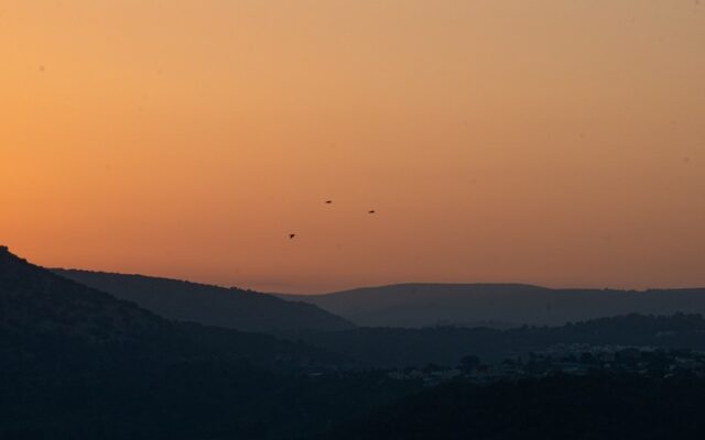Golden hour sunset silhouette over rolling hills and valley in Shlomi northern Israel with birds in flight